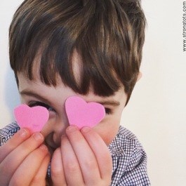 صبي holding hearts up in front of his face