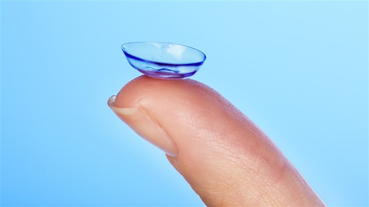 контакт lens on finger on blue background