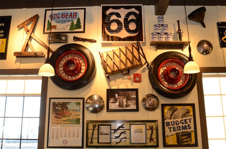 历史的 decorations pay homage to California's Route 66, such as an antique tire, luggage rack and suitcase, old motor oil cans, and an antique Esso calendar from June 1969.