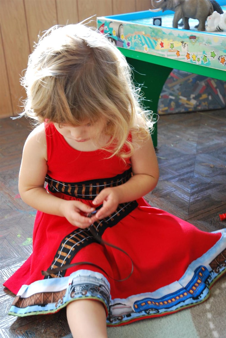 نموذج Sienna plays with her train-themed dress.