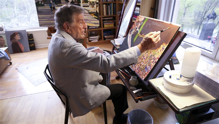 Im his New York art studio, Tony Bennett finishes a painting while sitting among several of his completed works. 