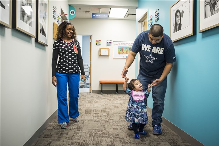 Eric Mata holds daughter Knatalye’s hands as she walks down the hall of a clinic at Texas Children’s Hospital.