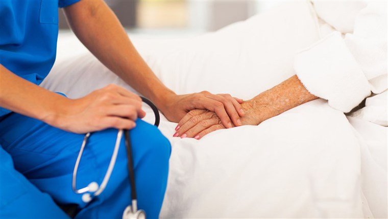 Zdravotní sestřička holds elderly patient's hand