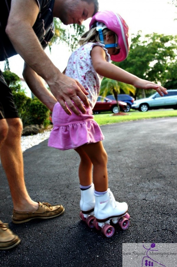 Papa helping daughter rollerskate