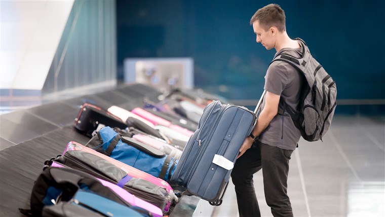 мъж getting his luggage at airport luggage claim