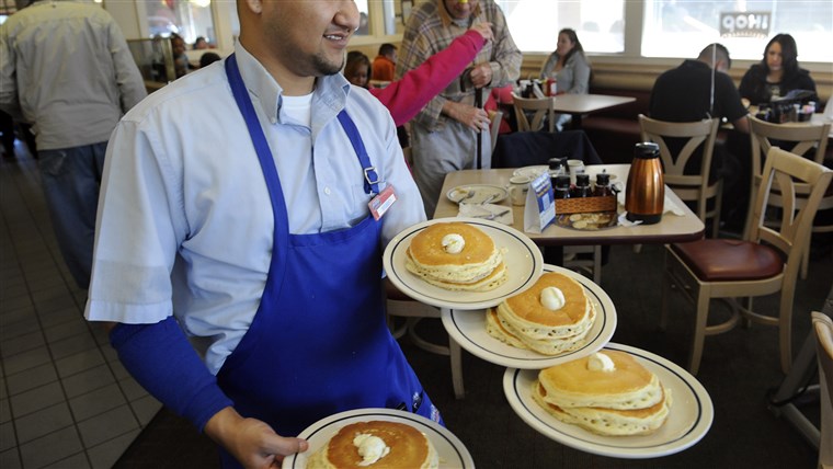 服务器 Ruben Avalos performs a balancing act with several plates of the free pancakes.