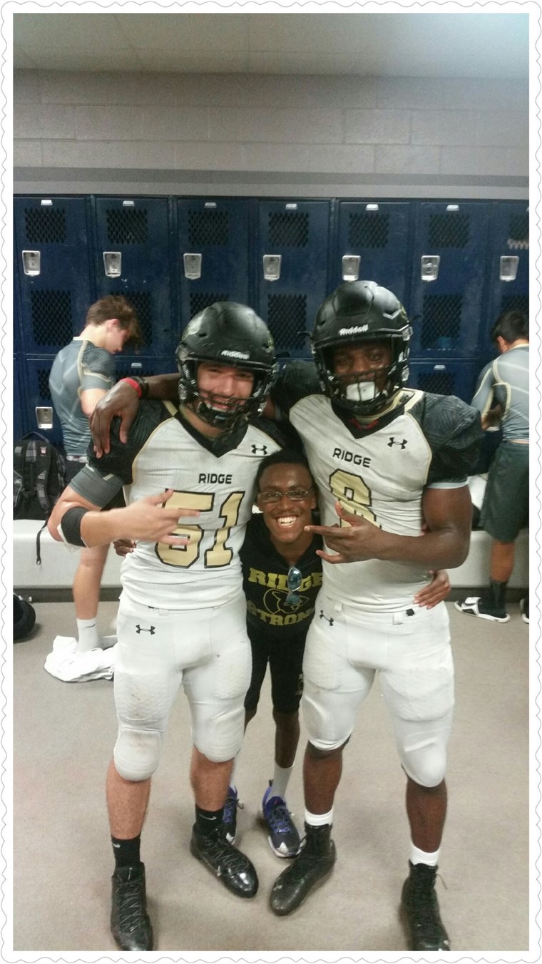 Norwood, the team manager, goofs off with a pair of Fossil Ridge football players.
