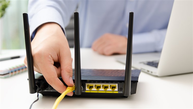 رجل plugs Ethernet cable into router